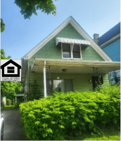 Green house with porch and awning.