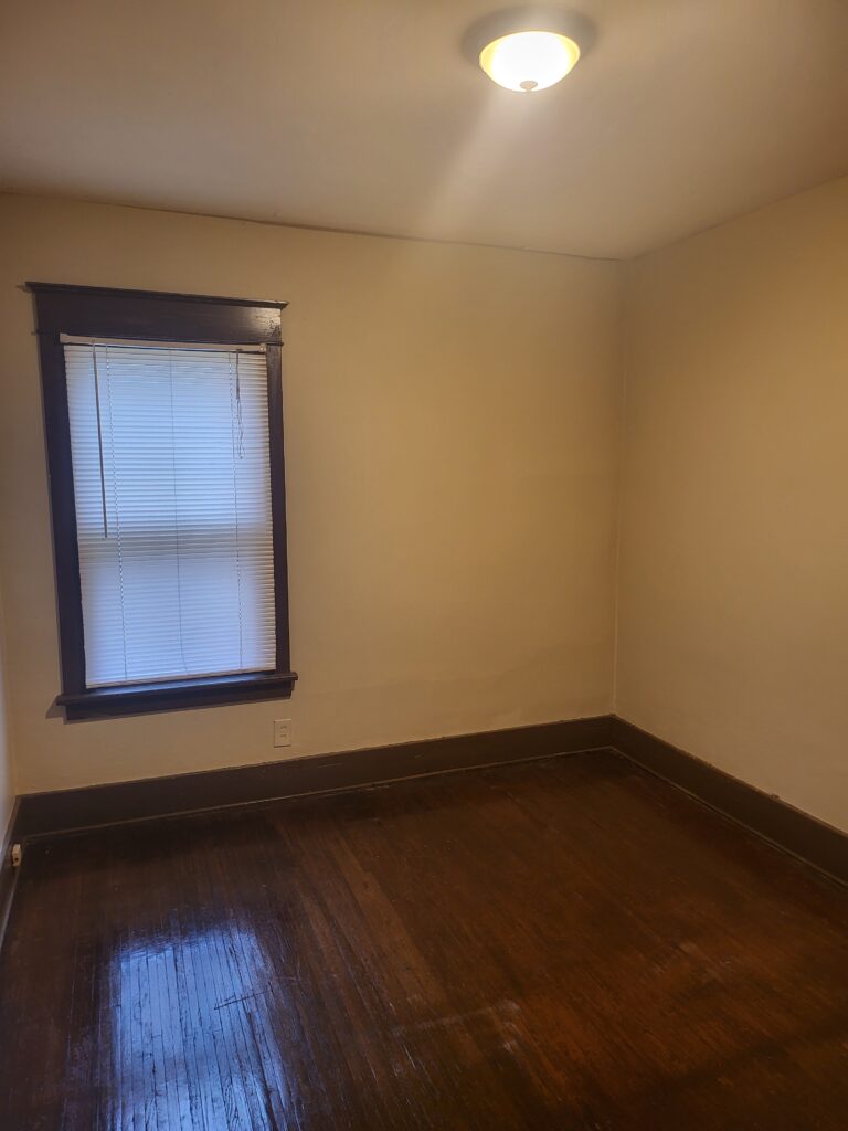 A bedroom with wood floors and white walls.